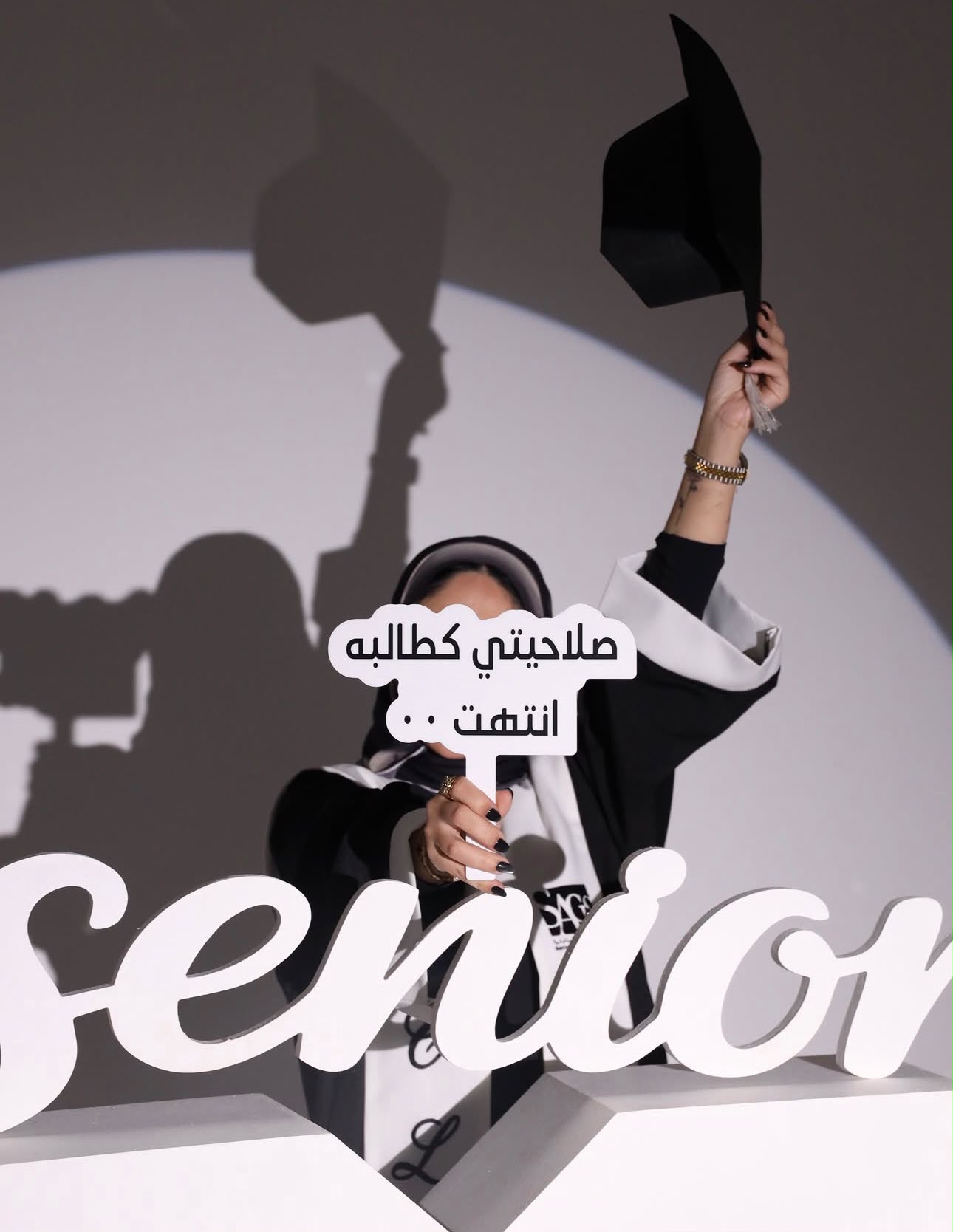 خريجة ترفع قبعة التخرج خلف مجسم senior